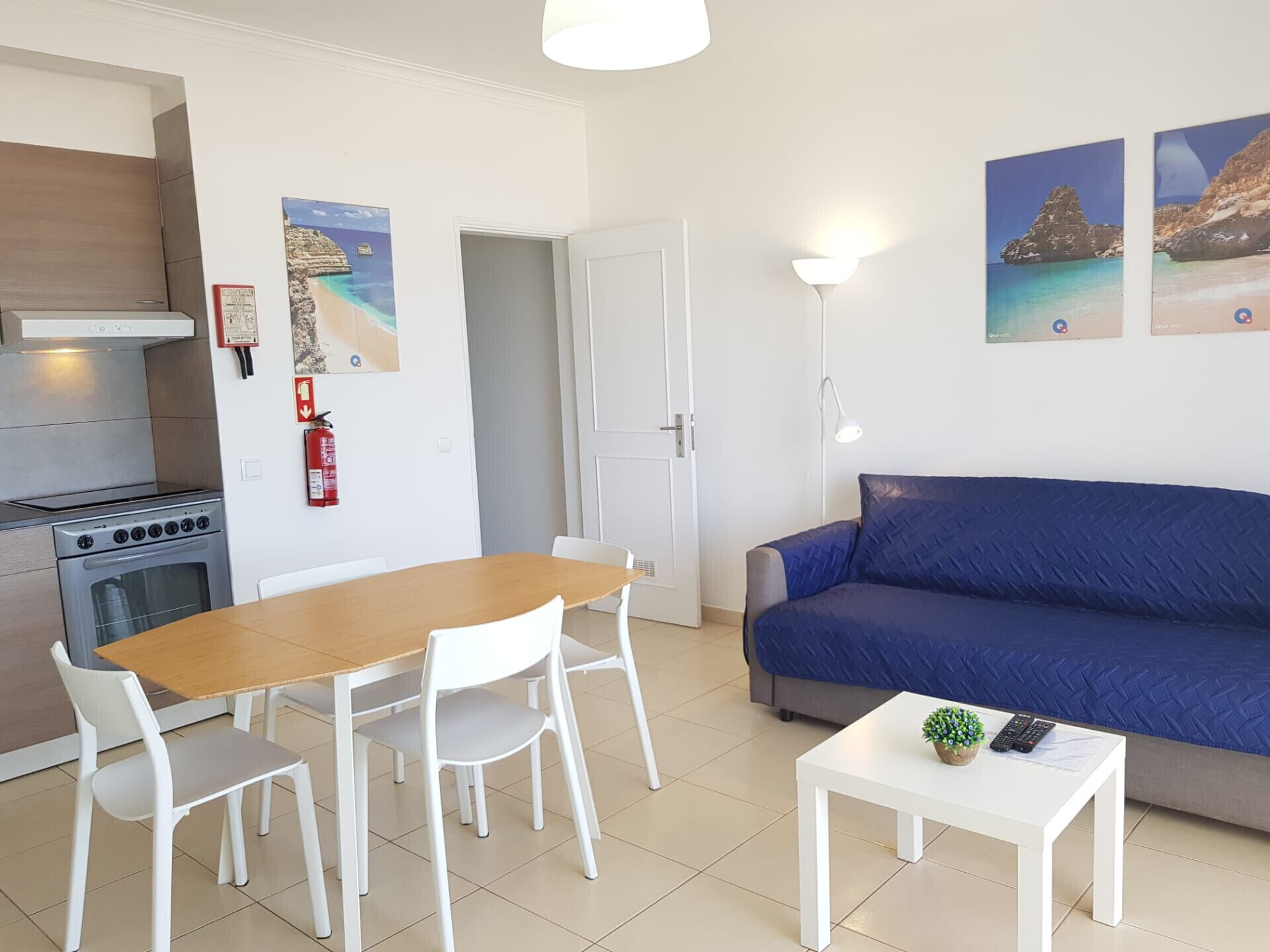 A compact living space with a kitchenette, a dining area, and a seating area with a blue sofa.