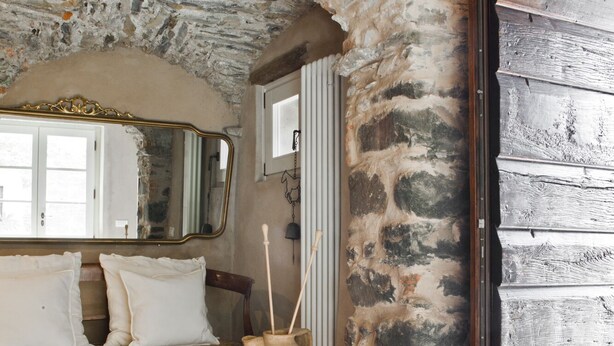 A rustic room with a stone wall, a wooden bench, a large mirror, and a metal cabinet. - Casale Amati Il Frantoio, near Cinque Terre. (ortonovo)