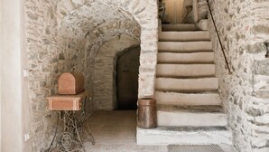 A stone staircase leading to a door, with a wooden box and a metal stand on the left. - Casale Amati Il Frantoio, near Cinque Terre. (ortonovo)