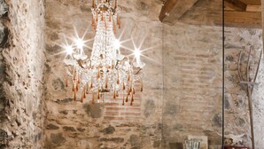 A rustic interior with a stone wall, wooden ceiling, and a chandelier. - Casale Amati Il Frantoio, near Cinque Terre. (ortonovo)