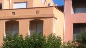 Un edificio con techo plano, varios balcones y fachada color beige.