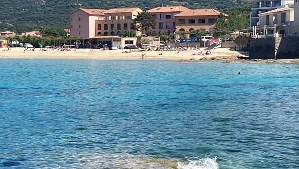 Un hotel frente al mar con varias construcciones, una playa de arena y agua cristalina.