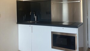 Una cocina moderna con armarios blancos, una campana extractora de acero inoxidable y un horno.
