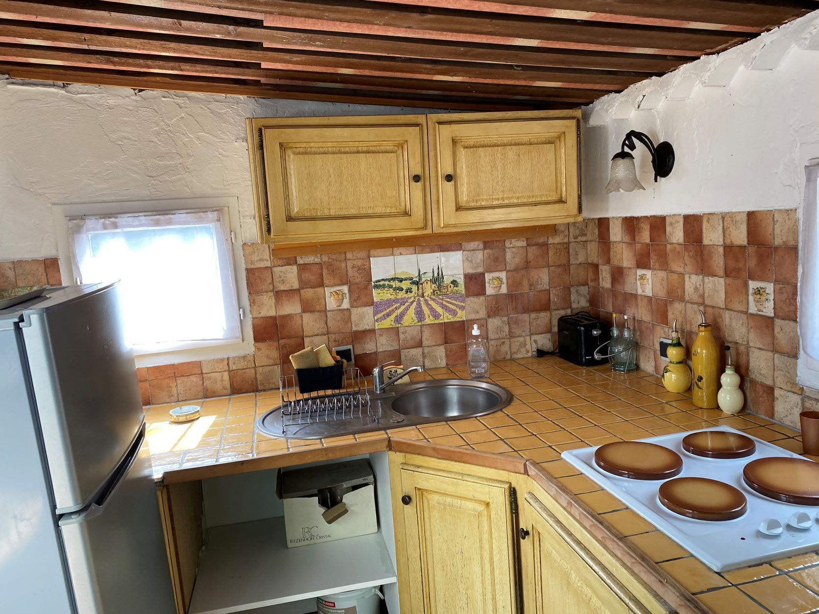 Una cocina compacta con armarios de madera, salpicadero azulejado, horno empotrado y refrigerador.