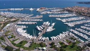 Une vue aérienne d’une marina où de nombreux bateaux sont amarrés en cercle, le tout étant entouré d’une ville côtière.
