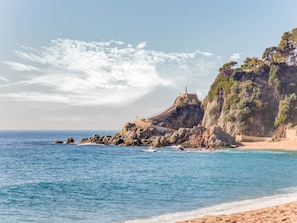 A coastal landscape with a rocky outcrop, a lighthouse, and a sandy beach. - Lloret De Mar: Apartment/ flat - Lloret de Mar (Lloret de Mar)
