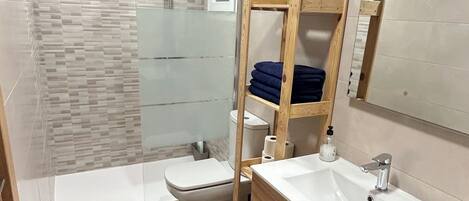A modern bathroom with a shower, toilet, and vanity.