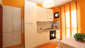 A kitchen with white cabinets, a sink, a stove, and a television mounted above the counter. - In the center of Agrigento (Agrigento)