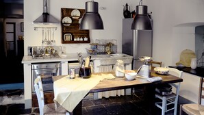 Una cocina con una mesa de madera, sillas blancas y una encimera de mármol.