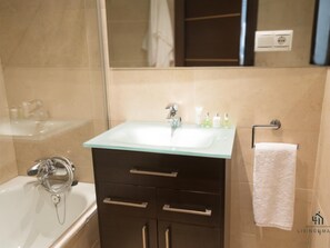 Ein Badezimmer mit einem Glaswaschbecken, dunklen Schränken, einem weißen Handtuch und einem Spiegel.