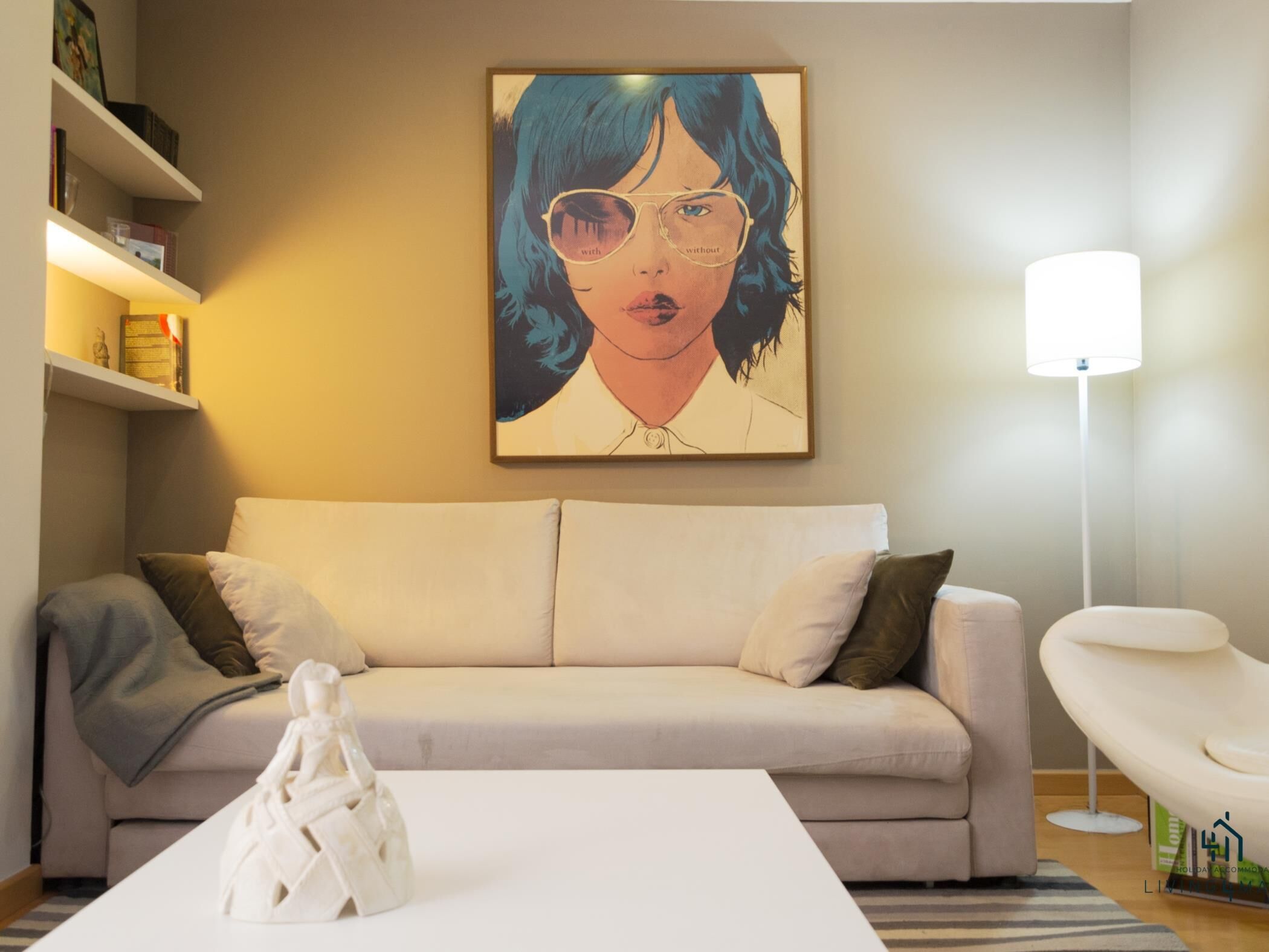 A living room with a beige sofa, a white coffee table, and a framed artwork above the sofa.