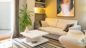 A modern living room with a sofa, a coffee table, a bookshelf, and a large painting on the wall. - Atarazanas Executive Living4malaga (M��laga ciudad)