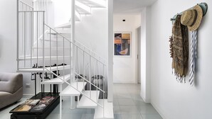 Um interior moderno com uma escada branca, um sofá e uma mesa de centro com revistas.