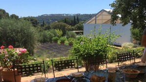 An outdoor dining table set with various dishes and glasses, surrounded by chairs with red cushions. - Seaside Villa Apartment with Large Terrace  2 mins from Renecros Beach (Bandol)