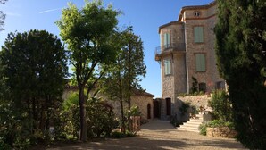 A stone building with a staircase leading to a door, surrounded by trees and greenery. - Seaside Villa Apartment with Large Terrace  2 mins from Renecros Beach (Bandol)