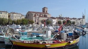 A marina with boats docked, a church with a bell tower, and residential buildings in the background. - Seaside Villa Apartment with Large Terrace  2 mins from Renecros Beach (Bandol)