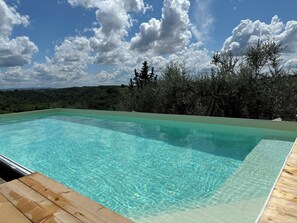 En rektangulär swimmingpool med klart, blått vatten, omgiven av ett trädäck.
