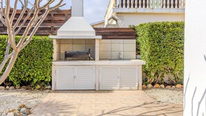 Cocina exterior con parrilla, pileta y dos armarios.
