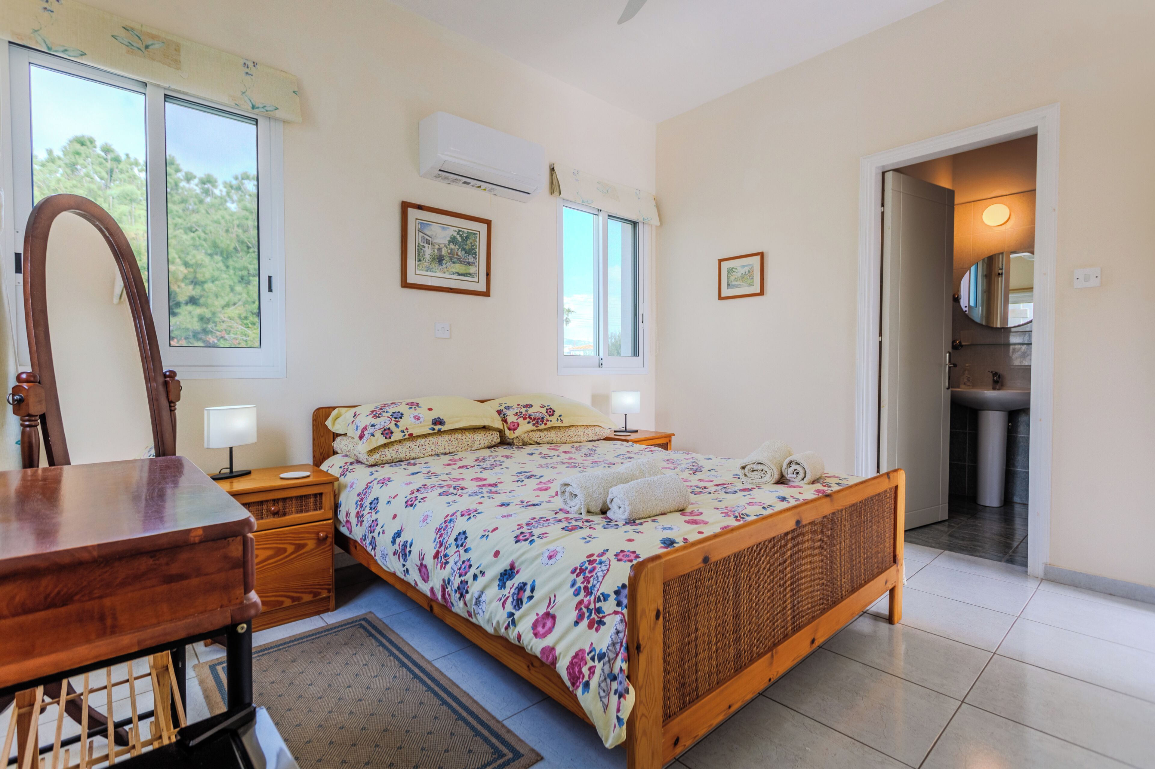 Une chambre à coucher avec un lit en bois, des tables de chevet, un miroir et une fenêtre.