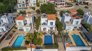 Zona residencial con varias casas de dos pisos, cada una con piscina y paneles solares.