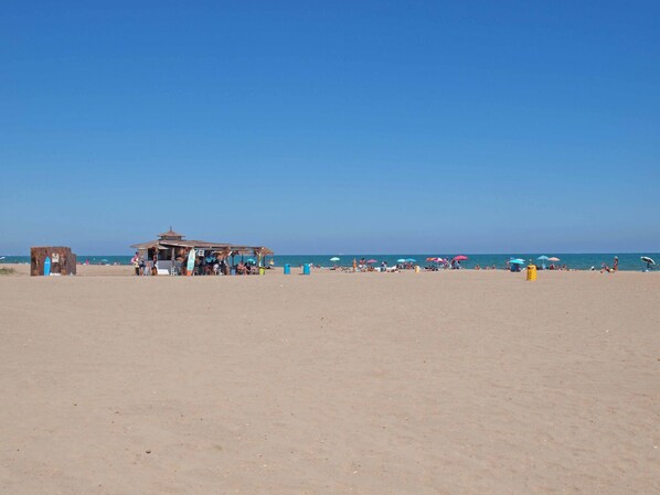 A beach with a small hut and umbrellas. - ApartUP Patacona Orchard (Alboraya)
