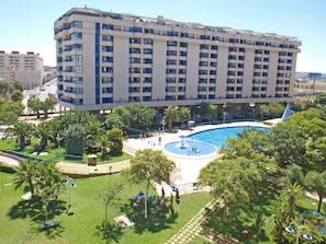 Un gran hotel con varios pisos, piscina y vegetación circundante.
