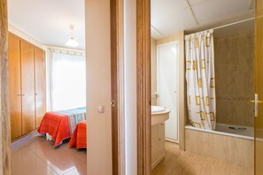 A room with a bed, a bathroom with a sink, and a shower. - ApartUP Patacona Orchard (Alboraya)