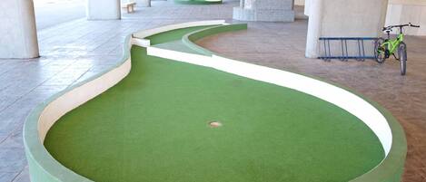 Ein grünes, künstliches Putting-Green mit einem in der Nähe abgestellten Fahrrad.