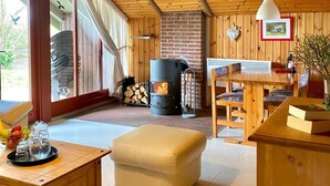 A cozy cabin interior with a wooden ceiling, a fireplace, a dining table, and a comfortable seating area. - Holidays with child and dog in Gartow am See (Gartow)