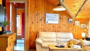 A cozy cabin interior with a wooden ceiling, a beige sofa, a wooden coffee table, and a sign on the wall. - Holidays with child and dog in Gartow am See (Gartow)