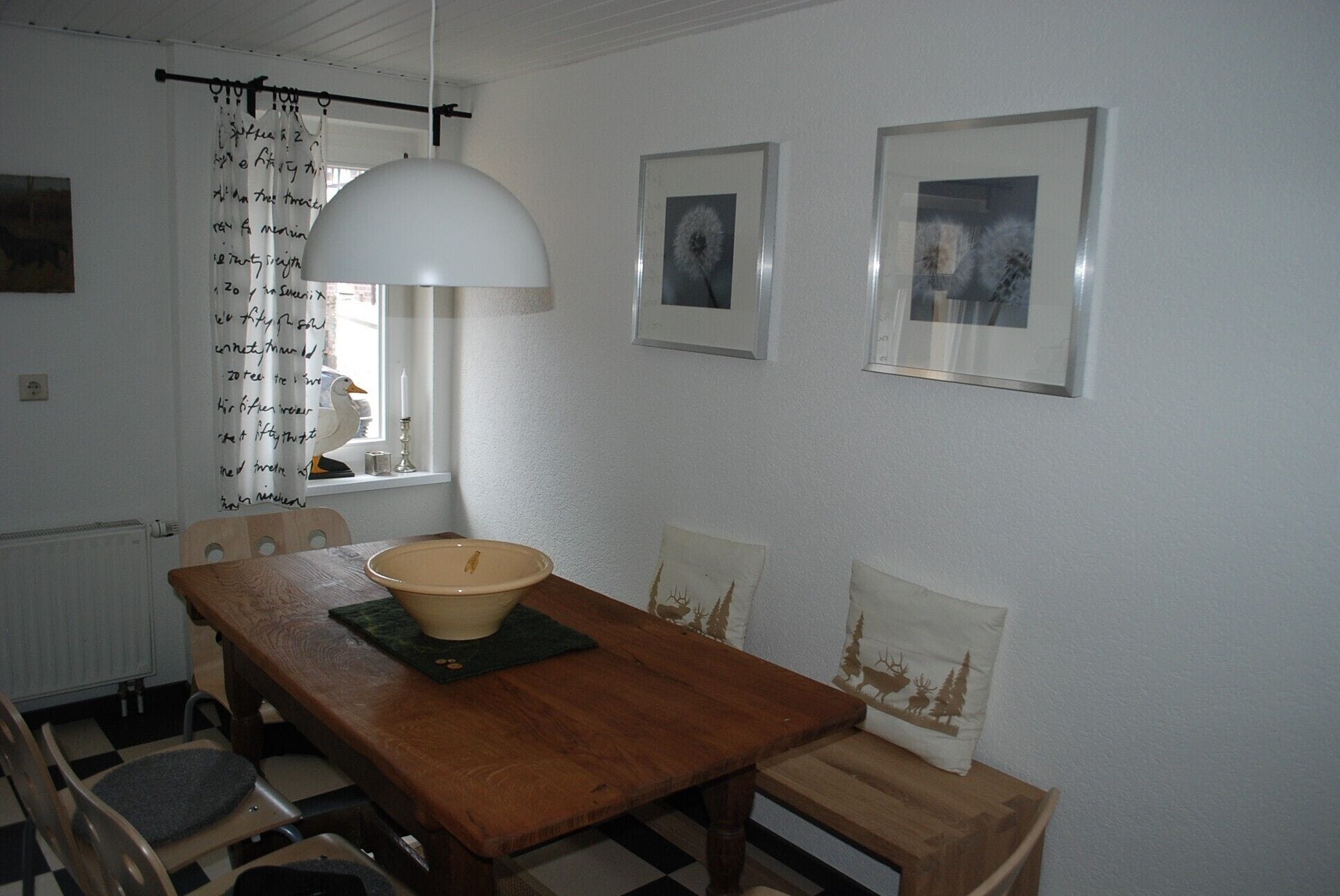 Un comedor con mesa de madera, sillas, un tazón y una lámpara colgante.