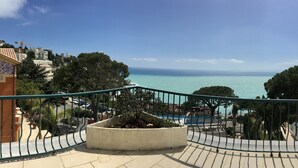 Ein Balkon mit Blick auf das Meer, einen Pool und umliegende Gebäude.