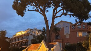 Ein großer Baum vor einem Gebäude mit Balkon und Ziegeldach.