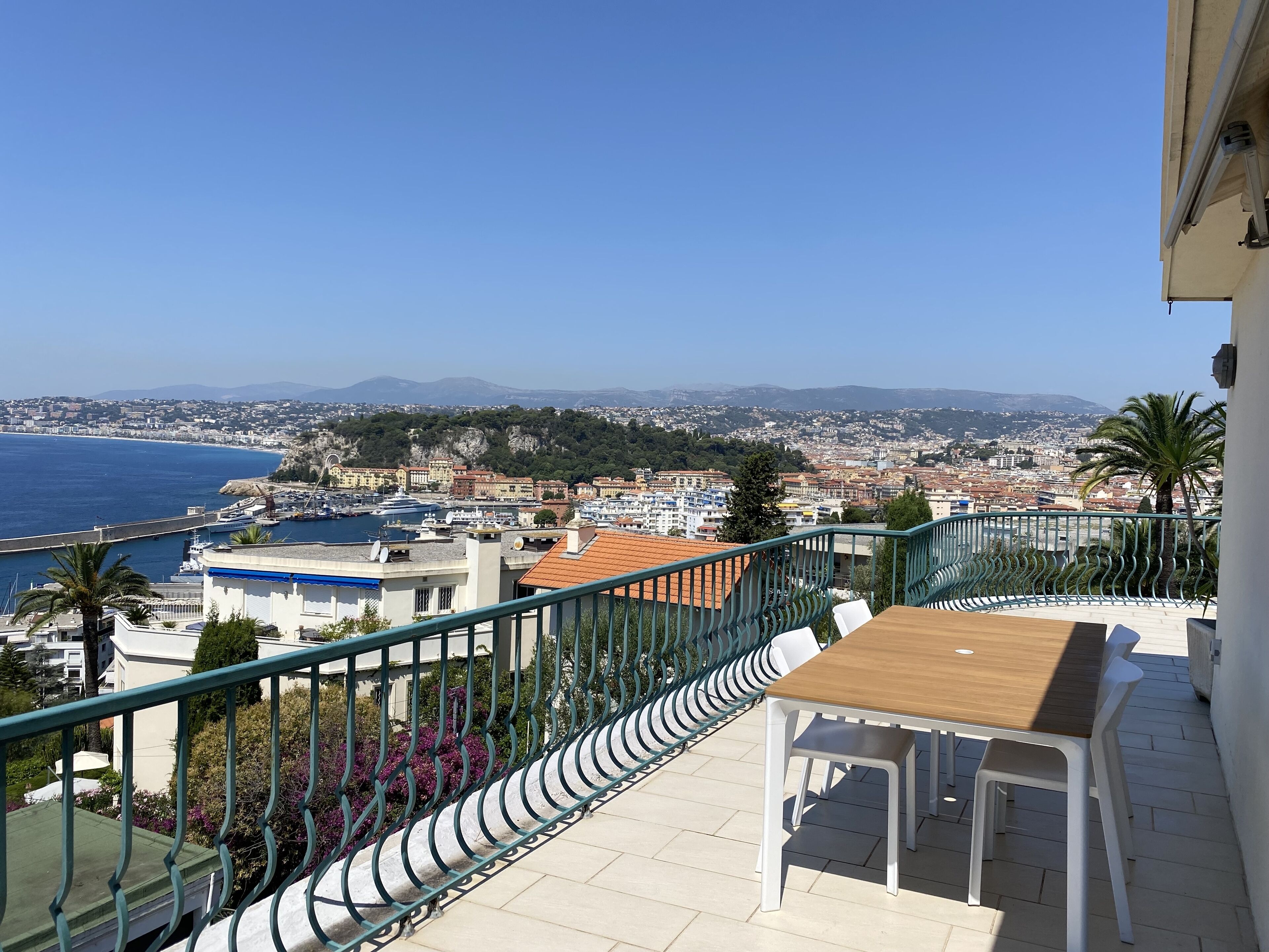 A balcony with a view of the sea, a dining table, and a railing.