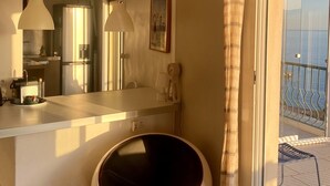 Eine moderne Küche mit einer zentralen Kochinsel, Pendelleuchten und Meerblick vom Balkon.
