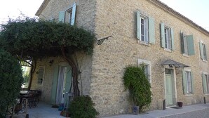 Un bâtiment en pierre doté d’un patio couvert, d’une porte et d’une petite table avec des chaises.