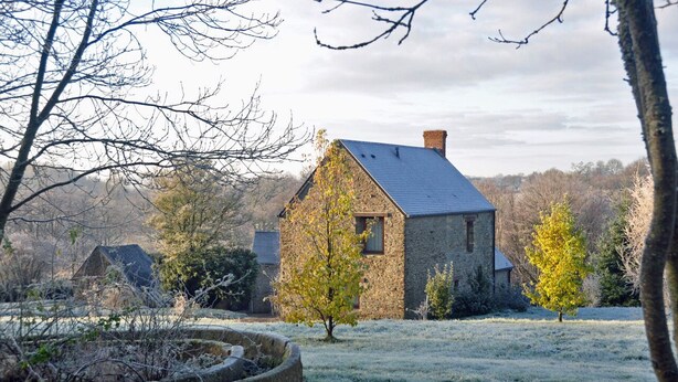 A stone house with a sloped roof and a chimney, surrounded by a frost-covered field and trees. - A breath of fresh air in Normandy (Condé-En-Normandie)