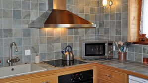 A modern kitchen with a stainless steel range hood, a built-in microwave, and a kettle on the countertop. - A breath of fresh air in Normandy (Condé-En-Normandie)
