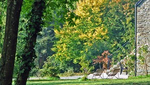 A stone building with a grassy lawn and outdoor seating area. - A breath of fresh air in Normandy (Condé-En-Normandie)