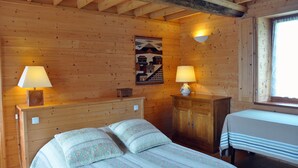 A wooden cabin room with a bed, two bedside tables with lamps, a wooden cabinet, and a window with curtains. - A breath of fresh air in Normandy (Condé-En-Normandie)