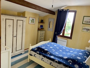 A bedroom with a bed, a wardrobe, a dresser, and a window with curtains. - House with garden, 500 m from the sea, 7 people, all comfort (Port-Des-Barques)
