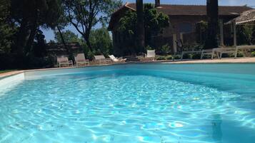 Une piscine aux eaux cristallines, avec des chaises longues et un bâtiment en arrière-plan.