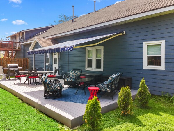 A blue house with a covered patio, outdoor furniture, and a grill.