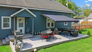 Ein Haus mit überdachter Terrasse, Gartenmöbeln und Rasenfläche.