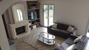 Un salon avec une cheminée, un canapé, une table basse et un téléviseur.