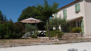 Un bâtiment doté d’un mur en pierre, d’une terrasse avec des chaises longues et d’une rangée de sphères métalliques.