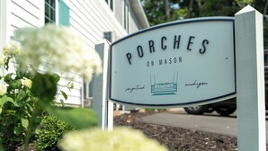 A sign for 'Porches on Mason' with a depiction of a porch and the state of Michigan.