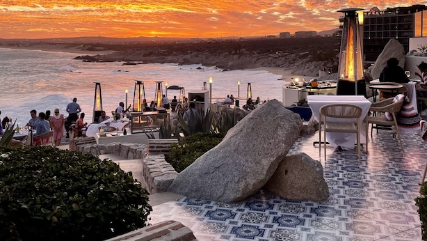 Terraço no telhado com área de estar externa, vista para o mar e um pôr do sol.