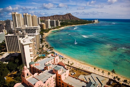 A coastal hotel with high-rise buildings, a beach, and a clear view of the ocean.