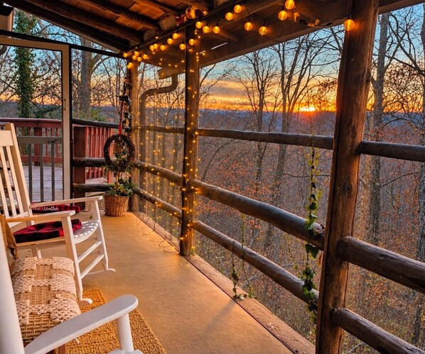 Un espacio de descanso techado al aire libre con vistas a árboles y al atardecer.